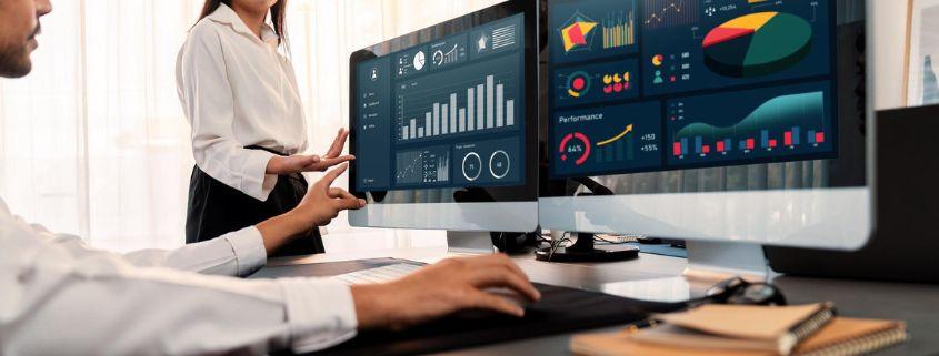 odoo-dashboard-margini-in-tempo-reale Un uomo e una donna guardano un computer che mostra grafici e dati.